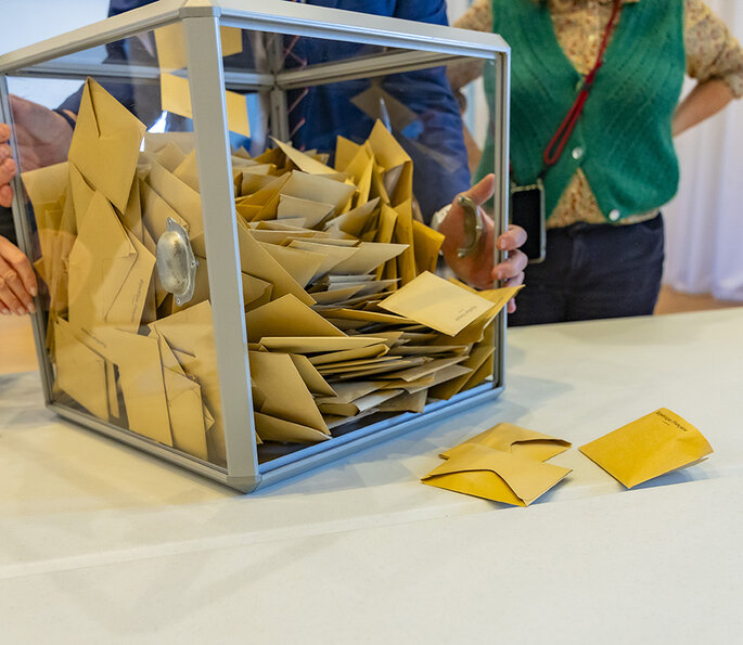 Le Président du bureau de vote a ouvert l'urne et verse les bulletins sur la table pour procéder au dépouillement.